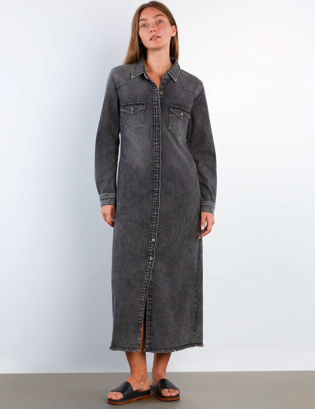 Woman wearing a long black denim dress against a white background