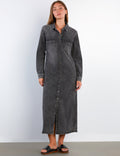 Woman wearing a long black denim dress against a white background