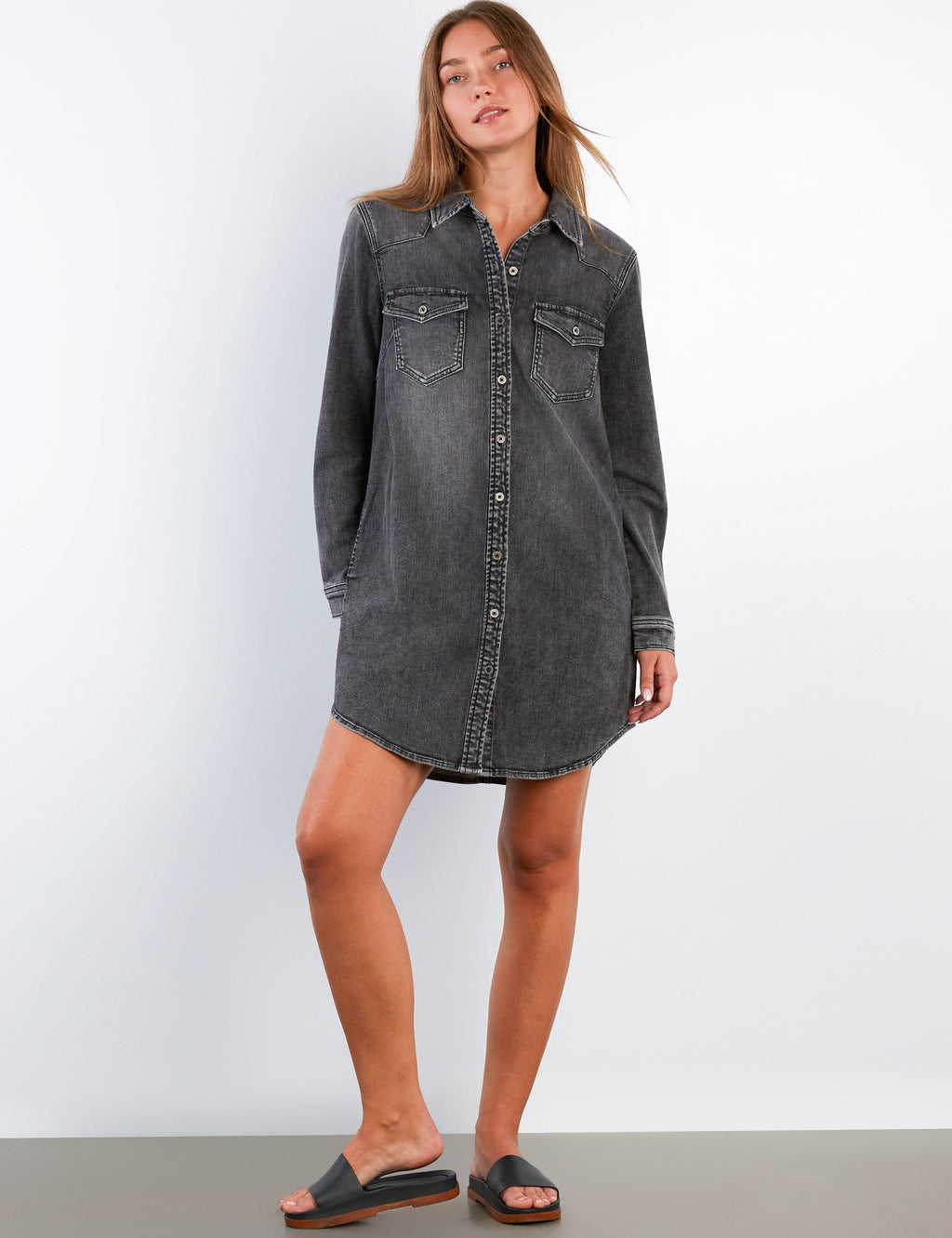 Woman wearing a black denim dress against a white background