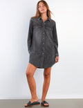 Woman wearing a black denim dress against a white background