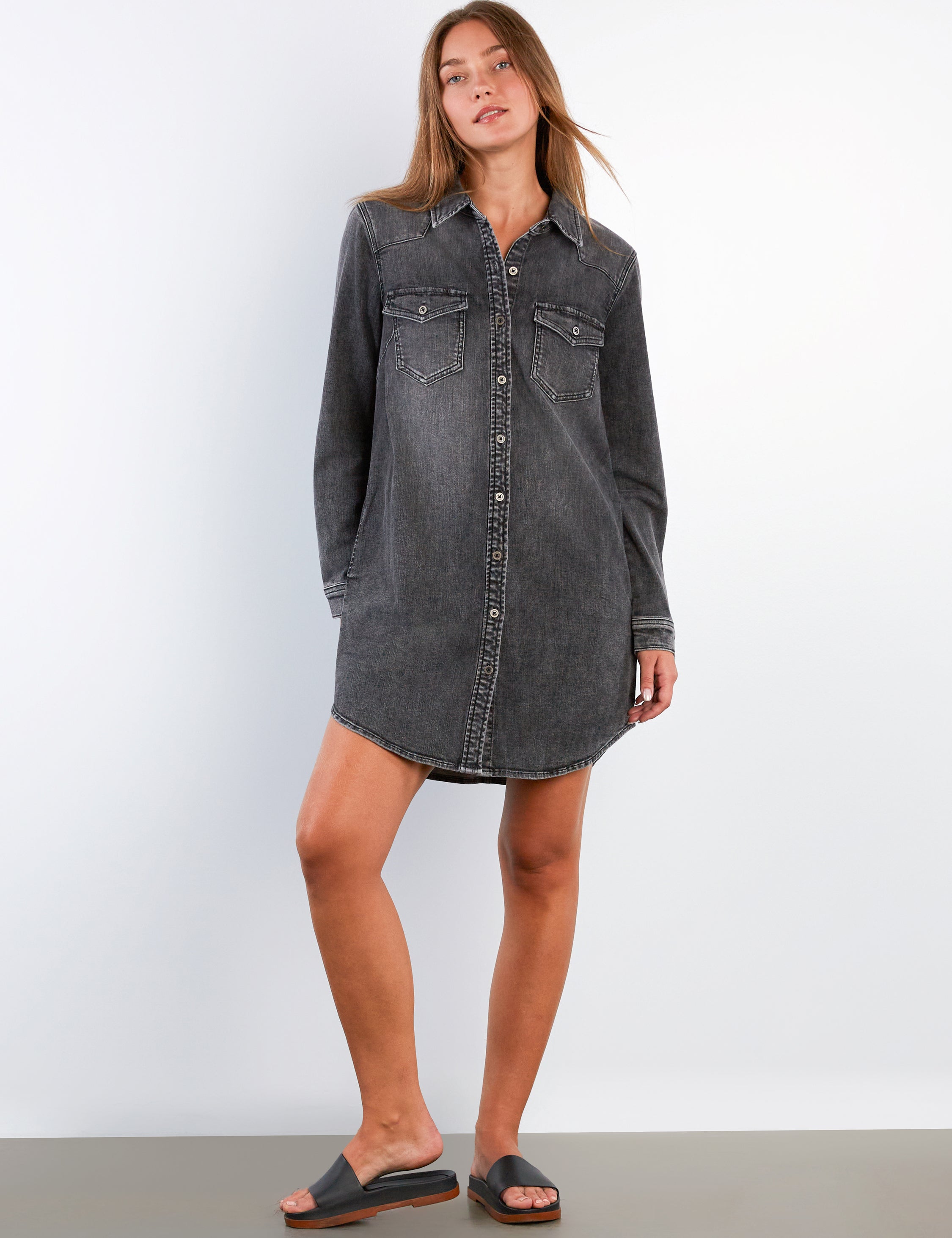 Woman wearing a black denim dress against a white background