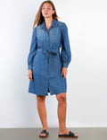 Woman wearing a blue denim dress against a white background