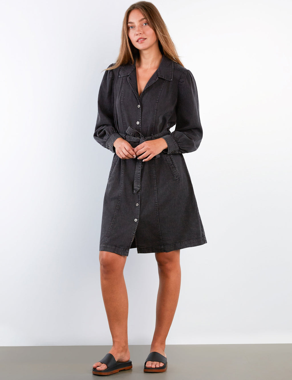 Woman wearing a black shirt dress against a white background