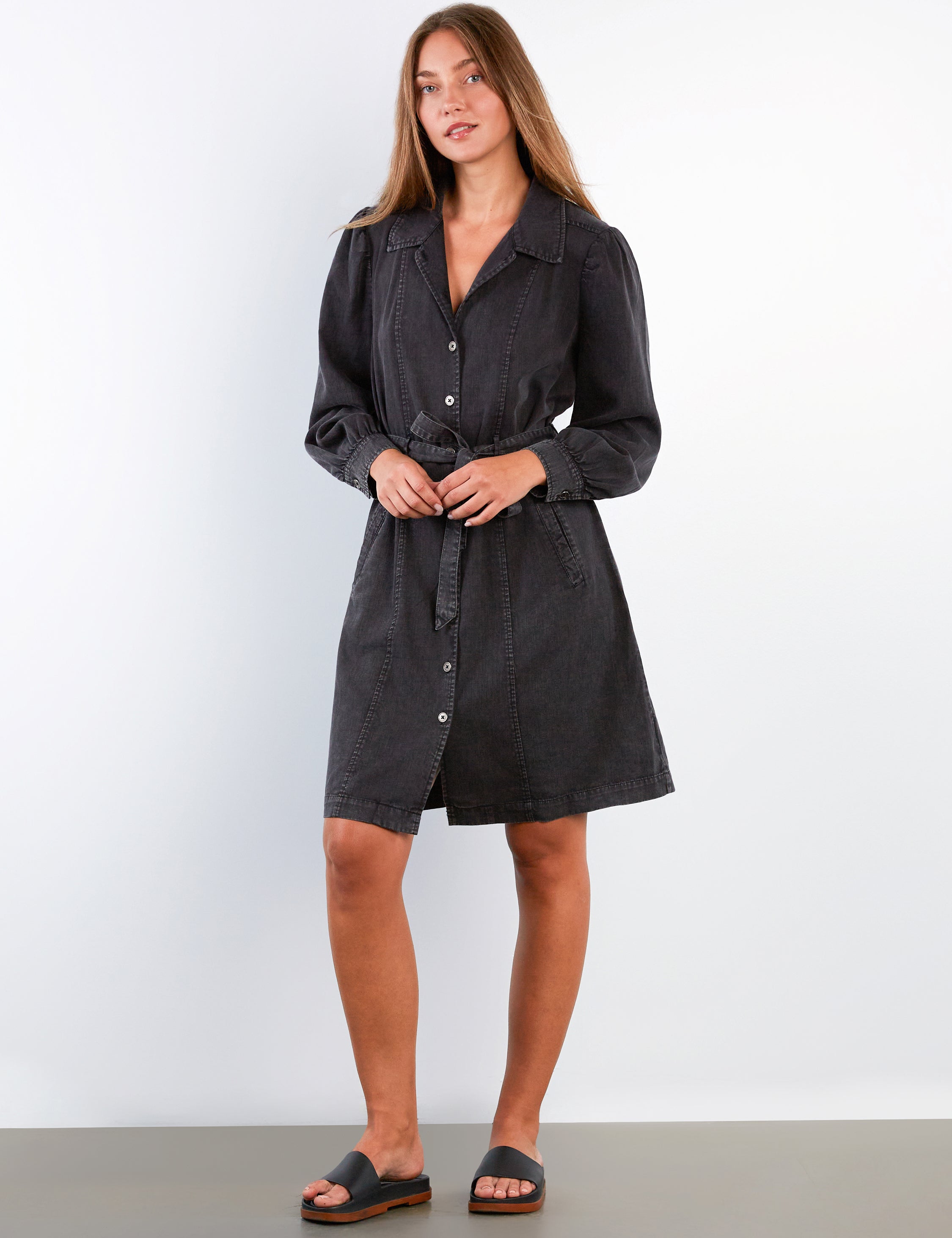 Woman wearing a black shirt dress against a white background